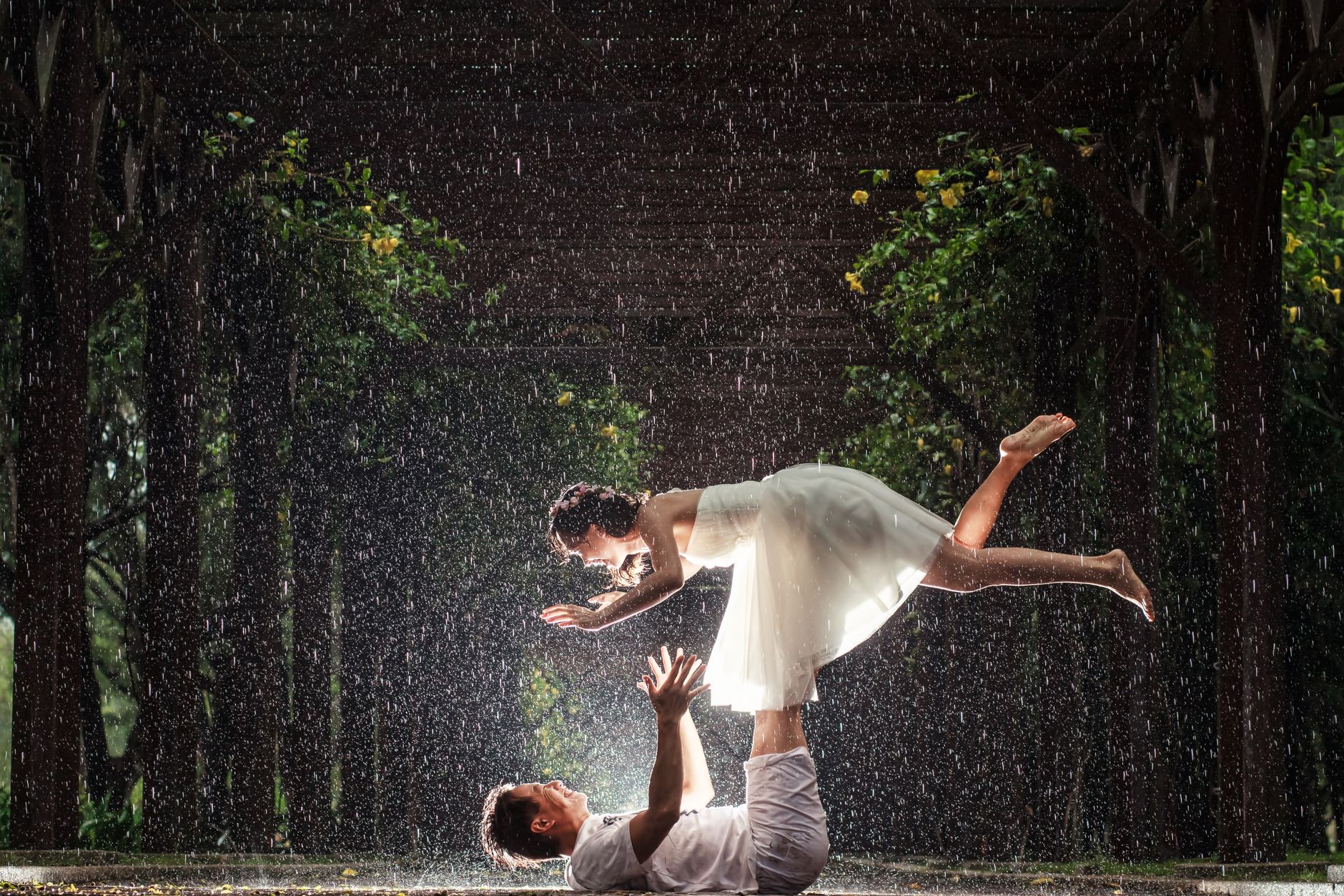 Creative rain-soaked wedding photoshoot featuring a couple in an artistic pose outdoors.