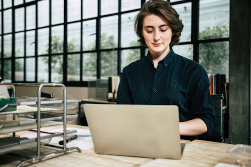 Free young business woman working laptop while consulting some invoices and documents in office Stock Photo