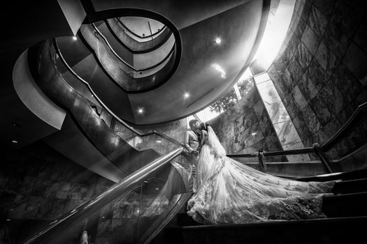 A breathtaking black and white photo of a couple kissing on a spiral staircase.
