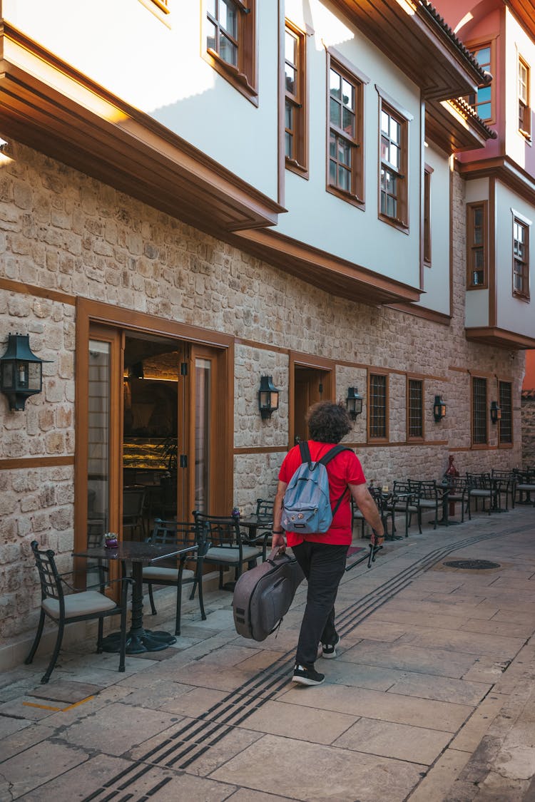 A Person With Backpack Carrying Guitar Case