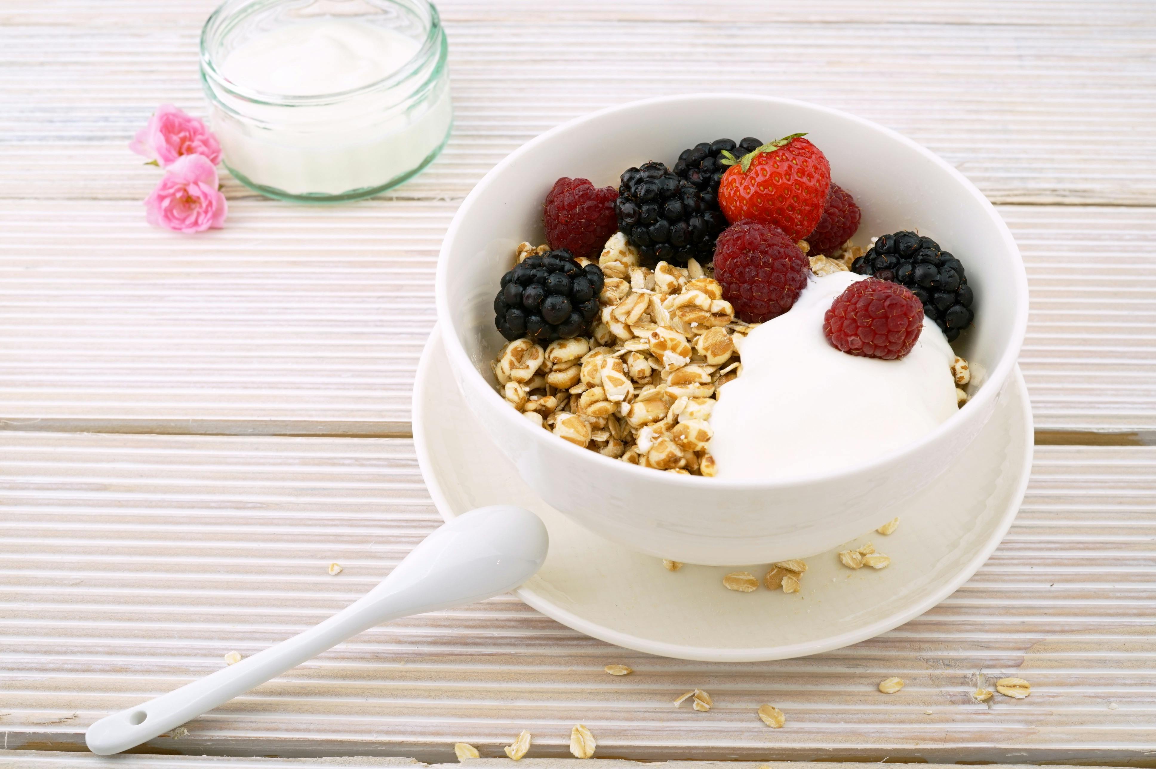 Menu Ngemil Anti Gemuk Semangkuk greek yogurt segar dengan taburan buah strawberry dan granola sebagai menu makanan rendah kalori