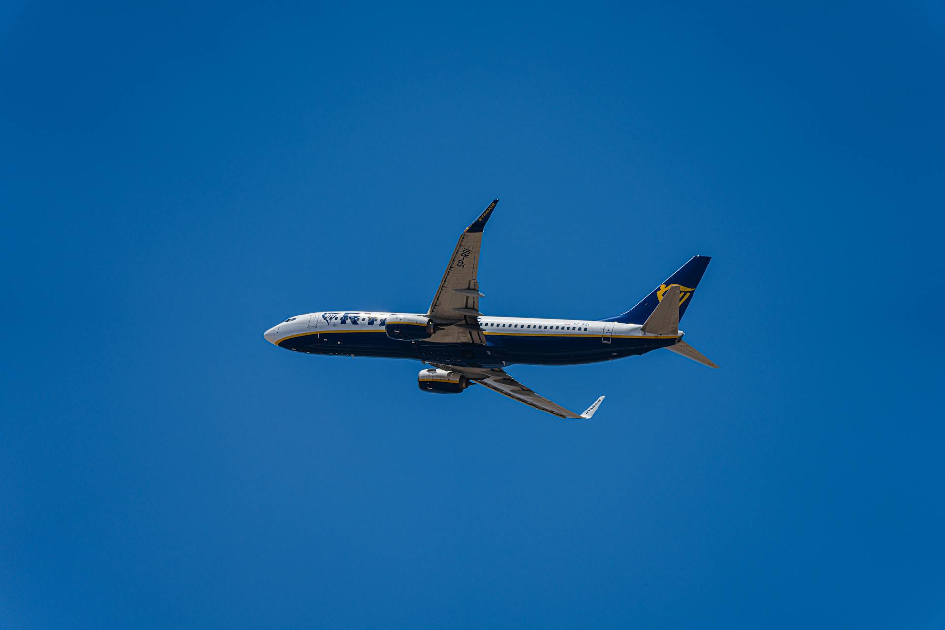 A commercial airplane flies high in a clear blue sky symbolizing travel and aviation.