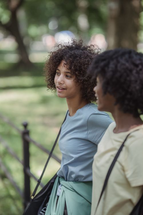 Free Two women enjoying a walk in the park, engaging in casual conversation on a sunny day. Stock Photo
