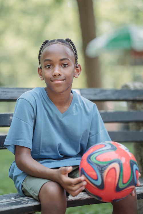 Free Portrait of a smiling teenage boy holding a colorful soccer ball outdoors on a sunny day. Stock Photo