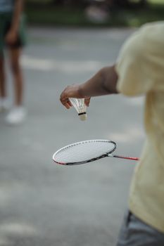 Close-up of a person playing badminton outdoors on a sunny day.