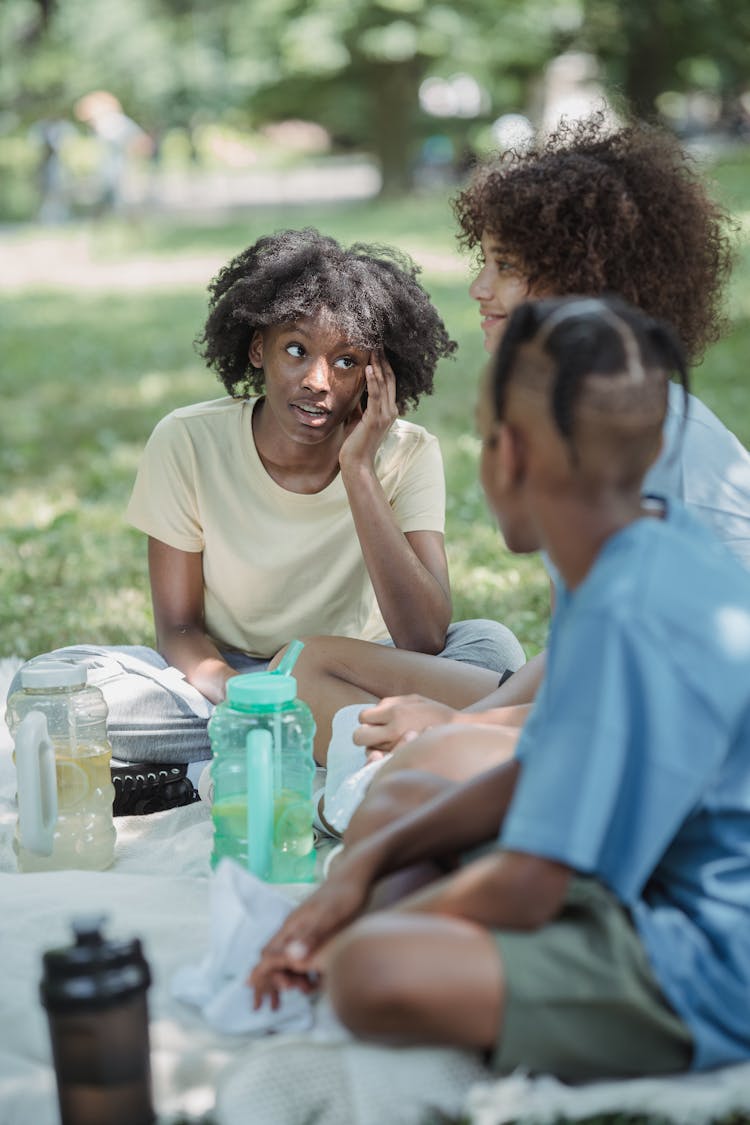 Three Teenagers Sitting On Lawn And Talking