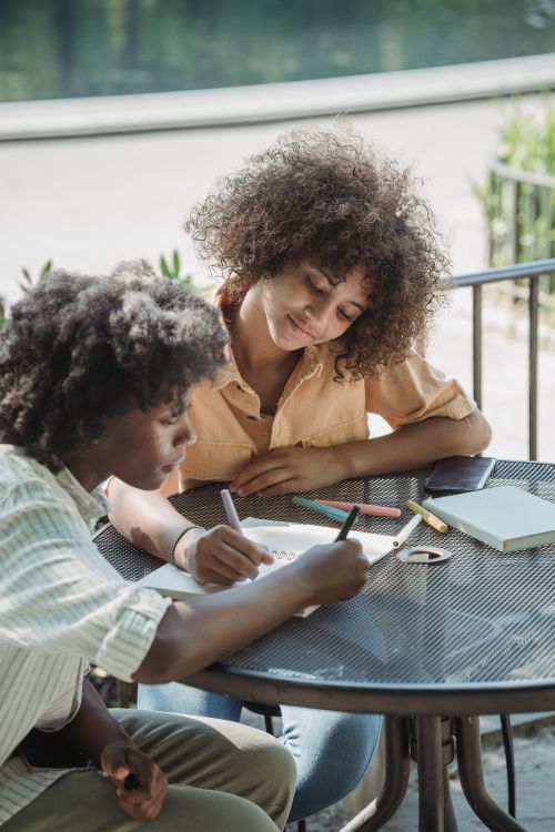 Free Two children drawing and painting outdoors at a table for creative fun. Stock Photo