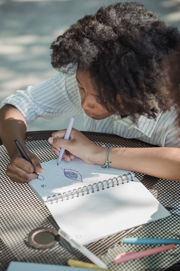 A Girl Drawing In A Notebook