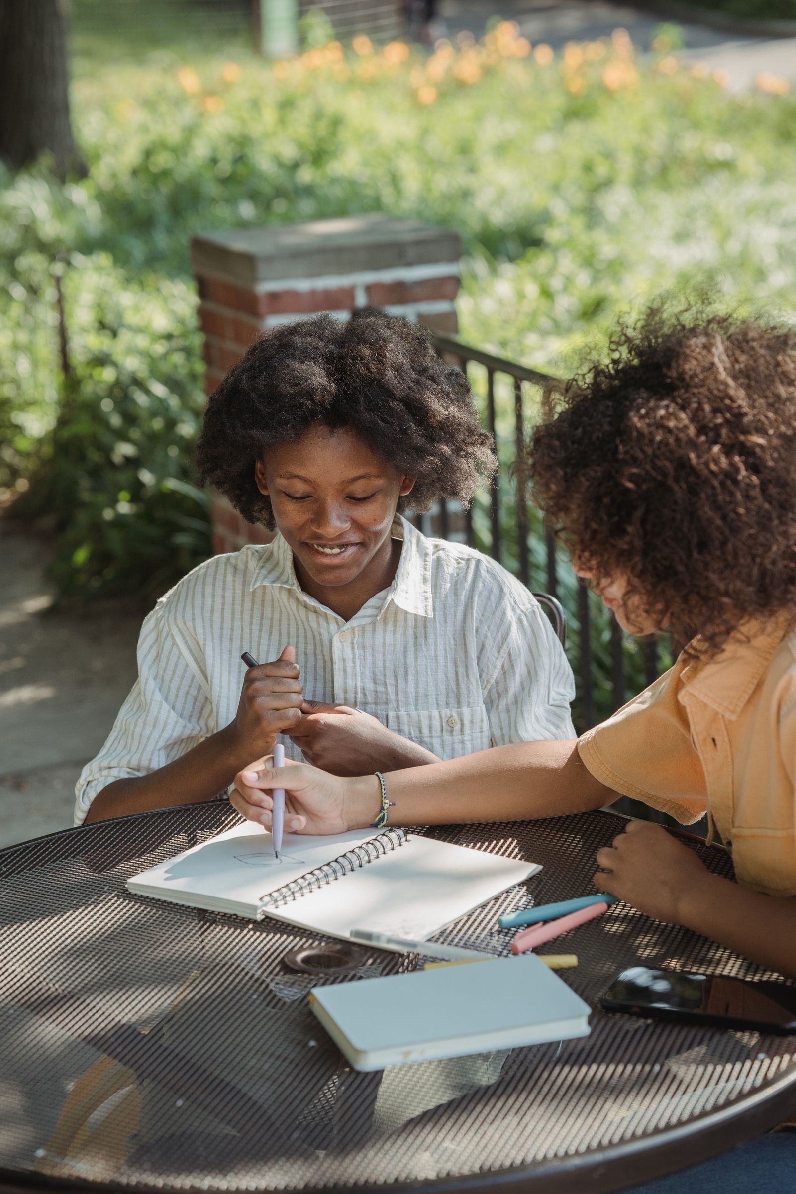 Dos personas jóvenes dibujando juntas en una mesa al aire libre
