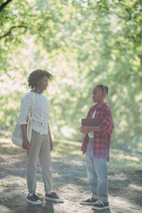 Free African American mother and child enjoy a warm summer day walking and talking in a park. Stock Photo