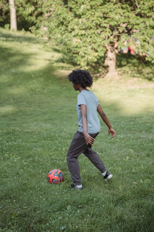 Free A young woman enjoys a sunny day playing football in a green park, showcasing active lifestyle and leisure. Stock Photo