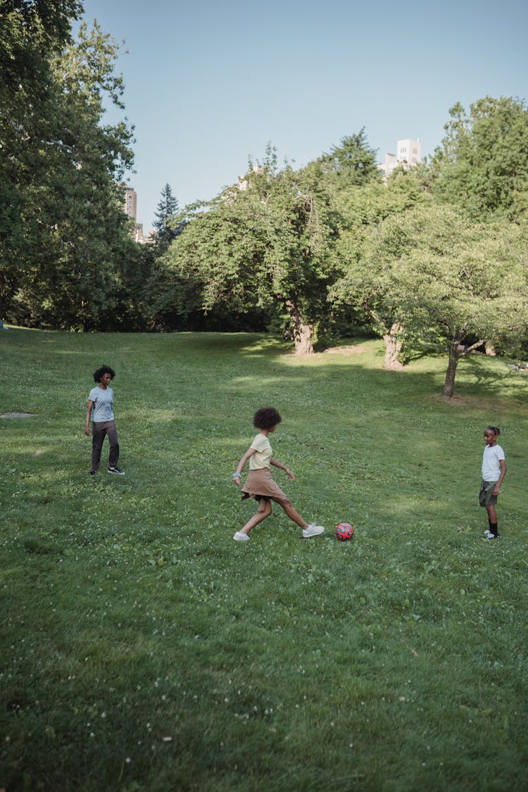 Teenage Girls And A Boy Playing Football In The Park 