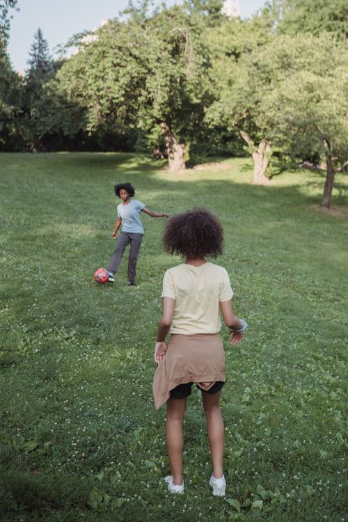 Free African American family playing football outdoors on a sunny day in the park. Stock Photo