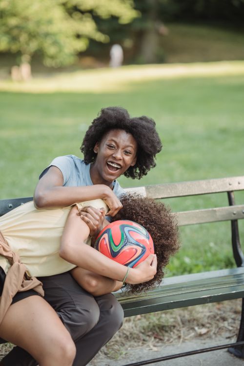 Free Mother and child playing joyfully on a park bench. Capturing a moment of laughter and bonding. Stock Photo