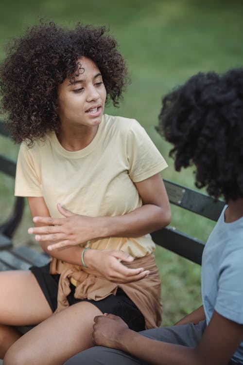 Teenage Girl Sitting on the Bench and Talking with her Friend 