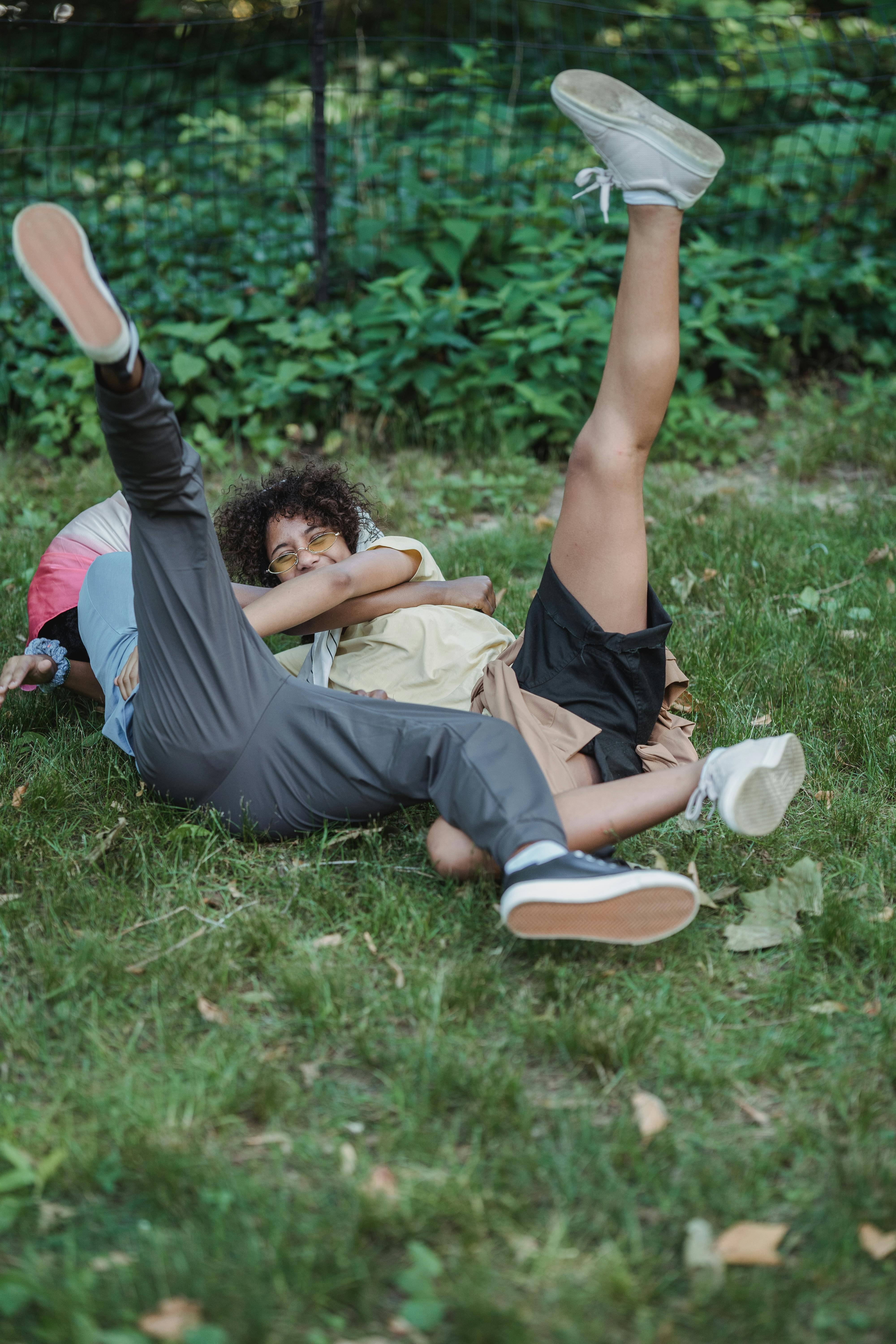 two teenage girls lying on the grass with legs raised