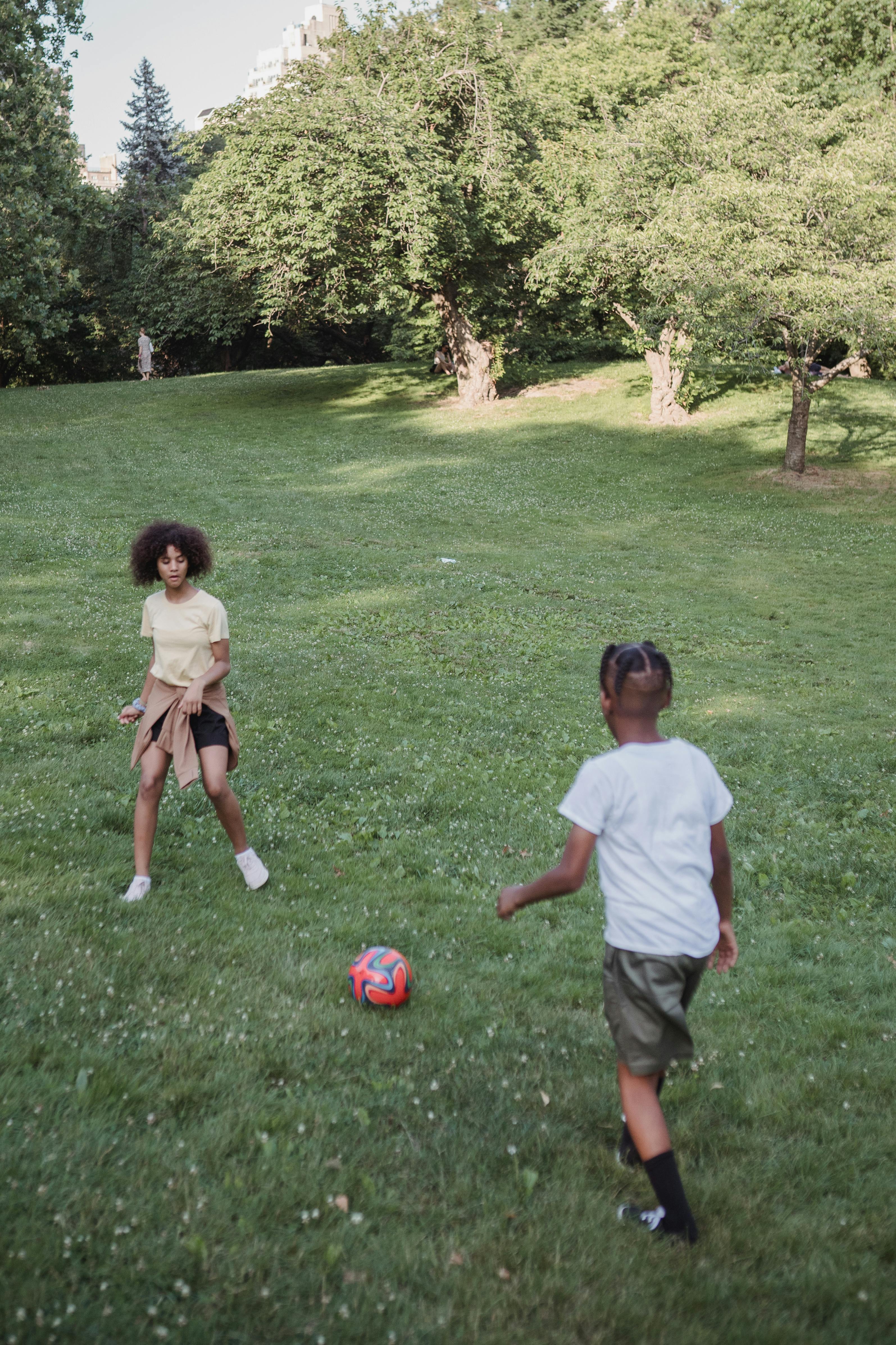 young boy and girl playing football outdoors