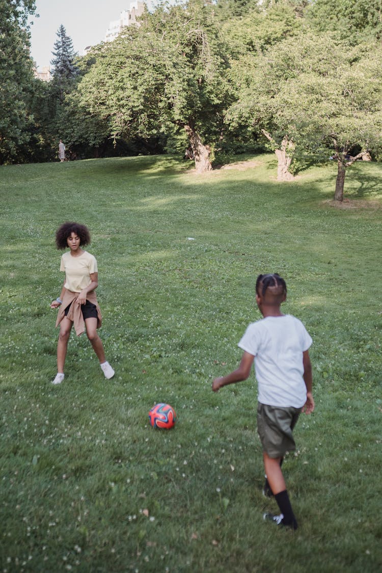 Young Boy And Girl Playing Football Outdoors 