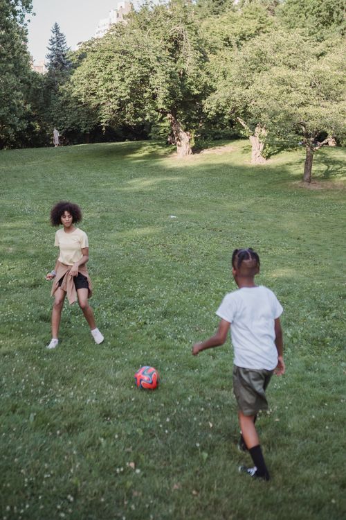 Free Two kids enjoy a sunny day playing football in a lush green park. Stock Photo
