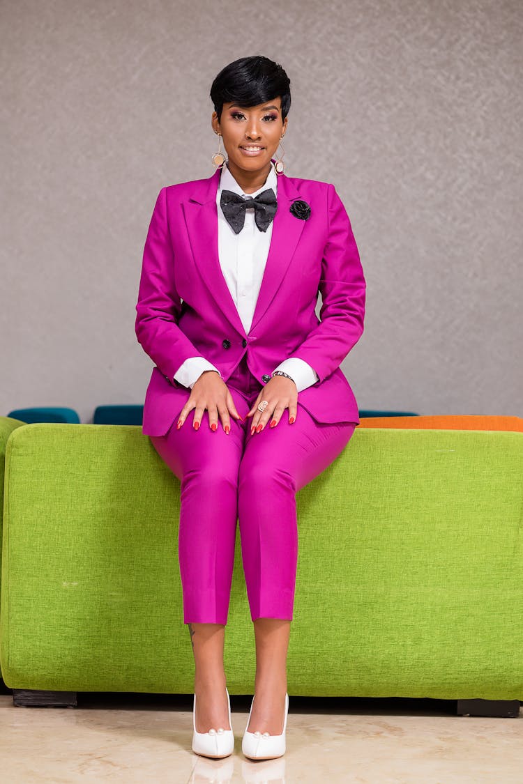 Woman In Pink Suit Sitting On Backrest Of Couch