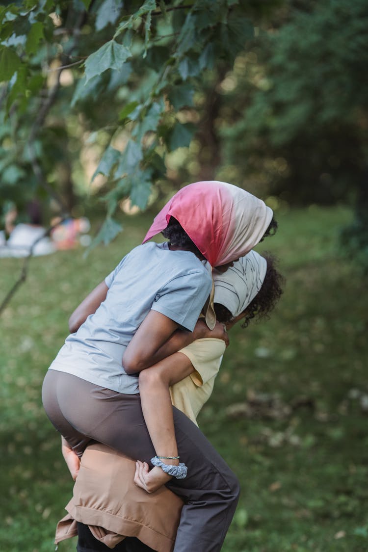 Girl Carrying Her Friend On A Back In Park