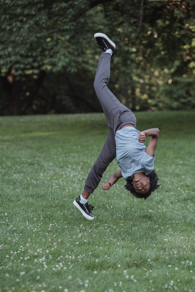 Girl Making A Cartwheel On Lawn In A Park