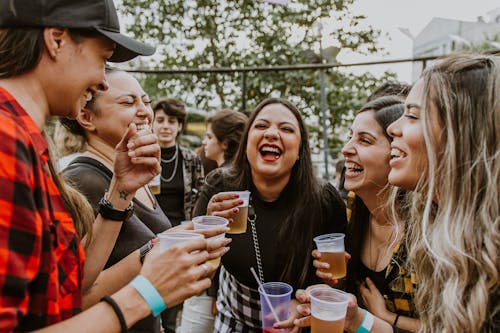 Women Laughing while Drinking Beer at Party