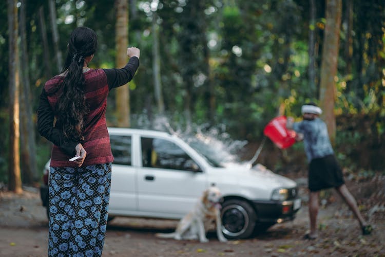 Woman Doing A Hand Sign To A Man Washing A Car