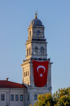 Vertical shot of Selimiye Barracks tower adorned with a Turkish flag in Istanbul.