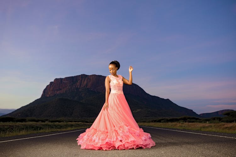 Woman Posing In Pink Long Gown Standing On Highway Road