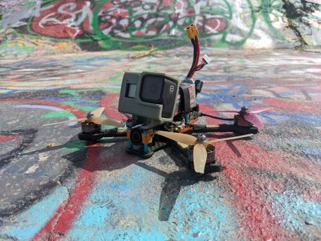 Close-up of an FPV racing drone with a camera on colorful graffiti background outdoors.