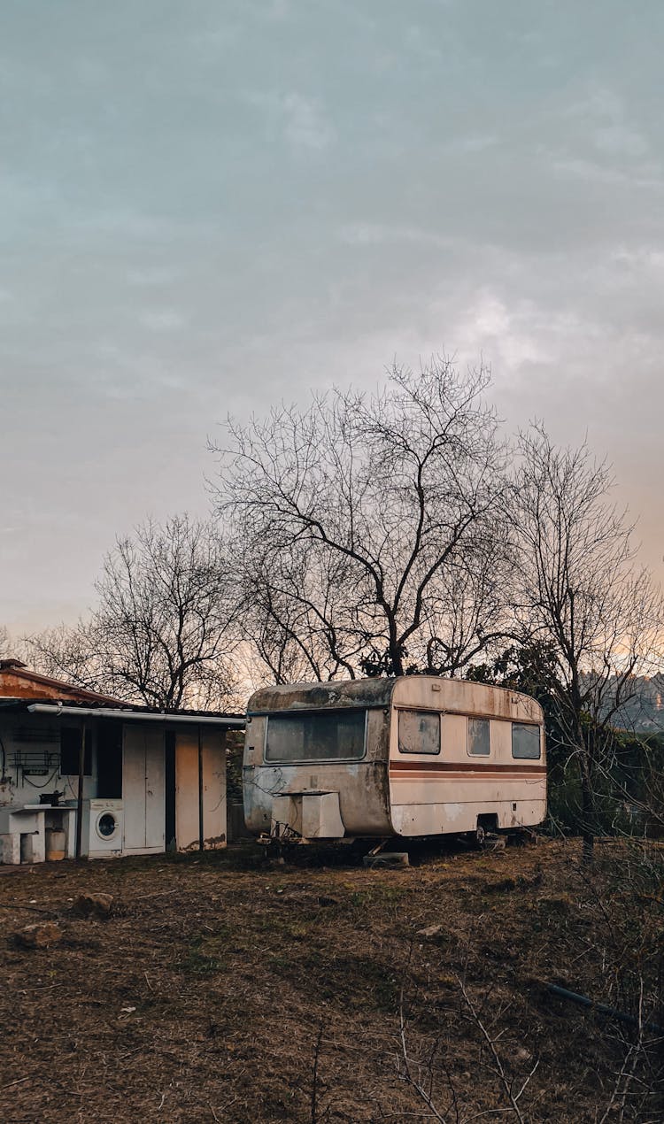 Abandoned Trailer Near A House And Dried Trees 