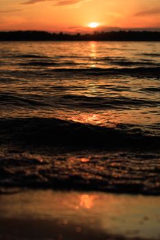 Capture of a serene sunset over the ocean's wavy waters, reflecting vibrant colors.