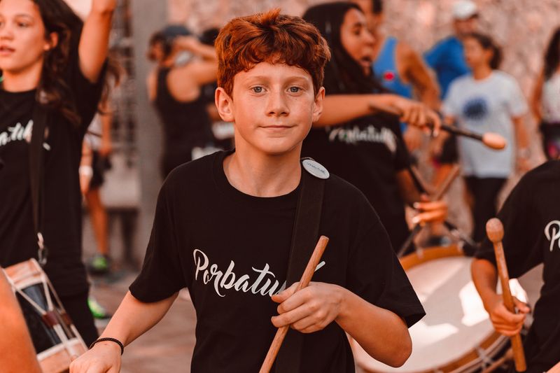 Niño tocando un tambor en un grupo de batucada