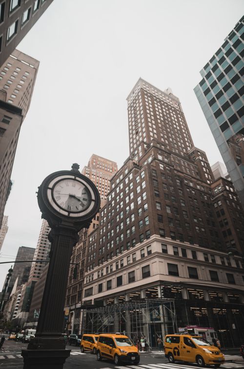 Free Classic New York street scene featuring a post clock, skyscrapers, and taxis. Stock Photo