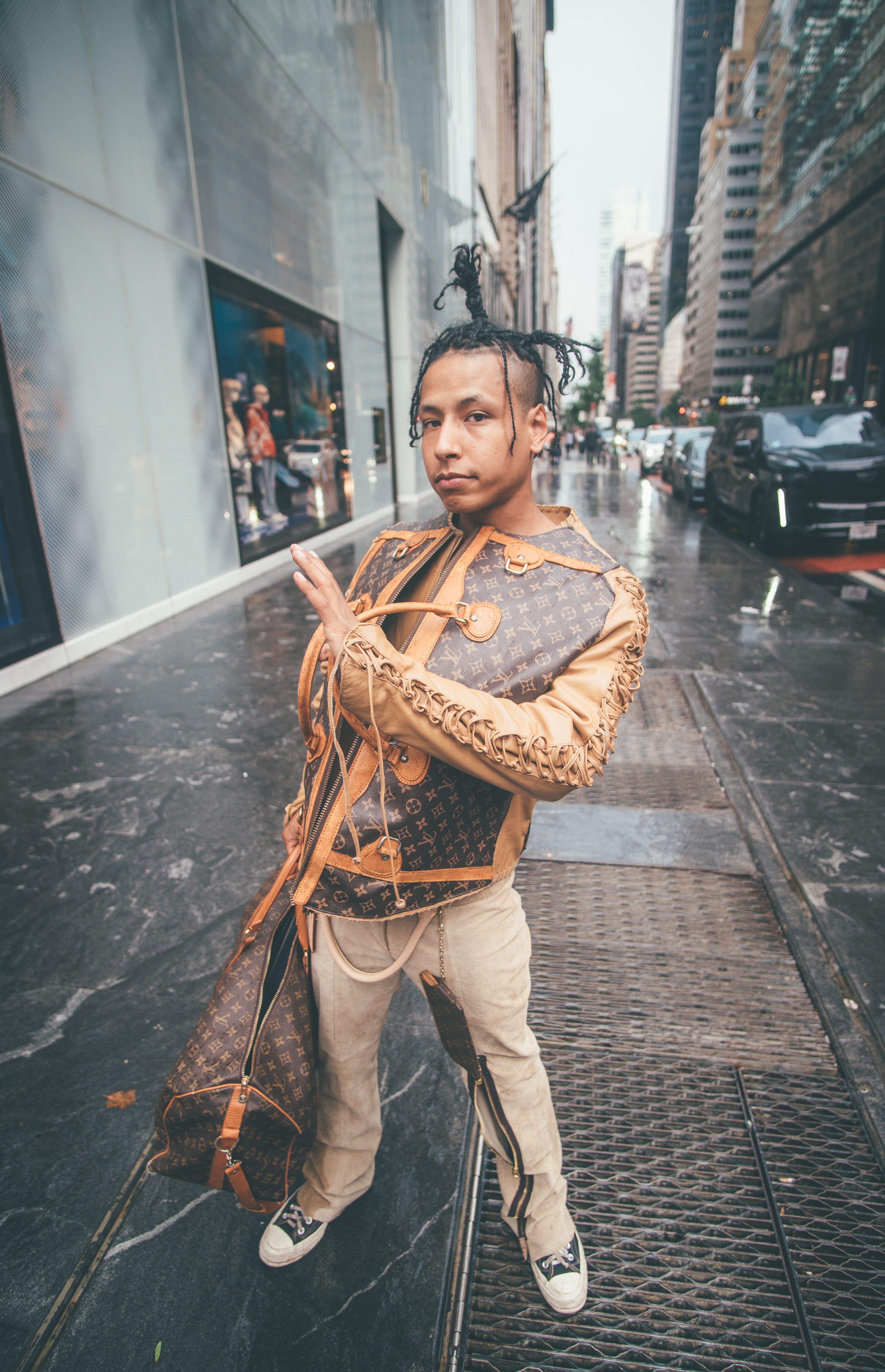 Stylish man in eccentric fashion stands confidently on city sidewalk.