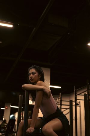 Athlete resting between sets on a rig in a dark gym. Photo by Connor Scott McManus on Pexels