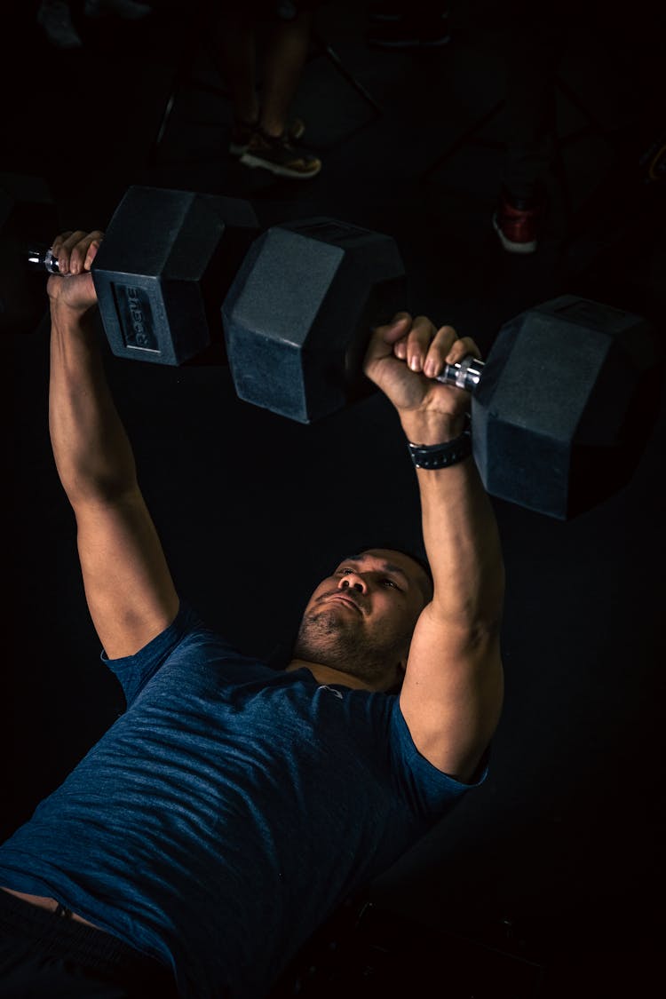 A Strong Man Lifting Dumbbells