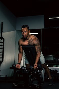 A muscular man working out with dumbbells in a gym setting, emphasizing strength and fitness.