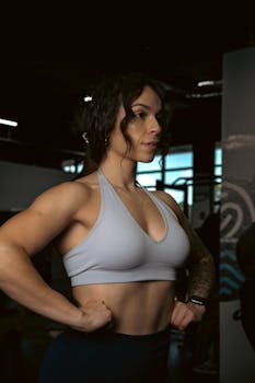 Fit woman in sports bra posing confidently in a gym setting, showcasing strength and fitness.