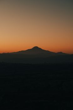 A breathtaking silhouette of a mountain against a vivid sunset sky, offering a serene and peaceful view.