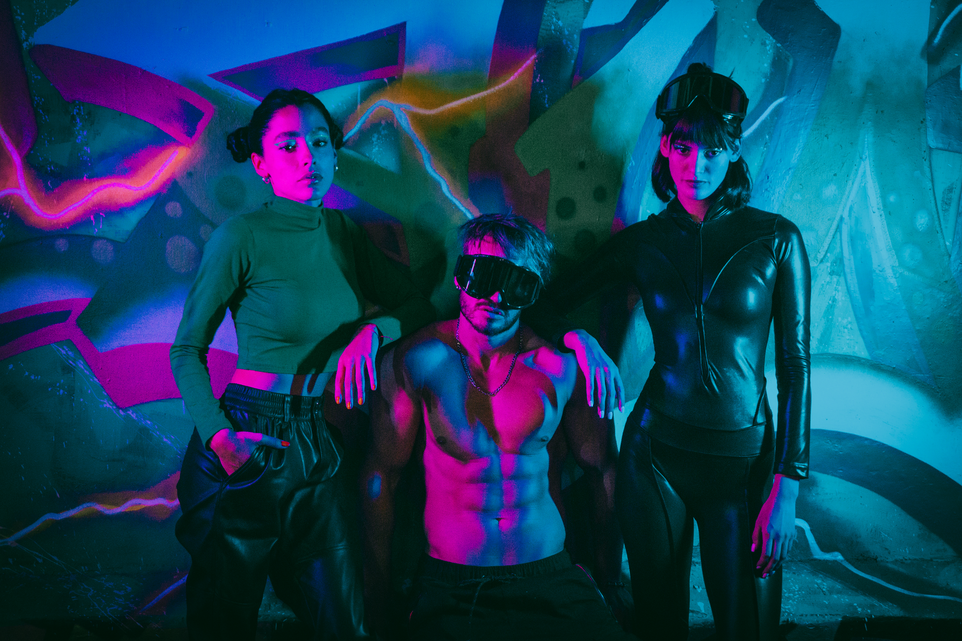 Group posing in stylish outfits against a neon graffiti wall under vibrant lights.