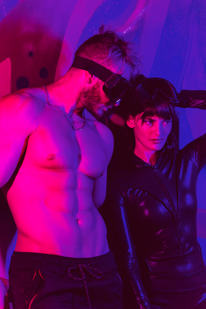 Stylish couple in a cyberpunk theme with neon lighting wearing futuristic accessories.