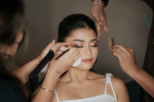 Close-up of a woman preparing for a fashion photoshoot with professional makeup artists.