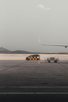 Airport runway scene with an airplane wing and ground vehicle in Athens, showcasing travel and transportation.