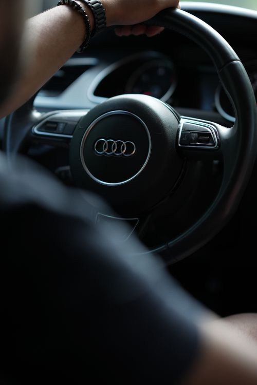 Free A close-up of a person holding the steering wheel of an Audi car, showcasing interior details. Stock Photo