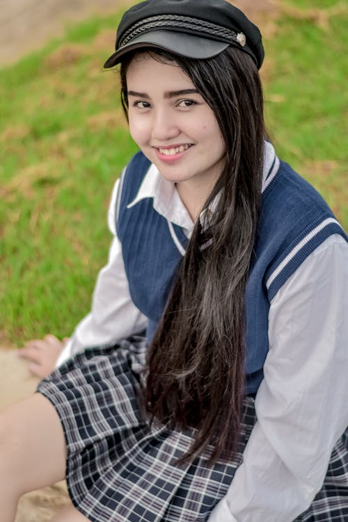 Woman in Blue and White Dress Shirt Sitting on Grass Field