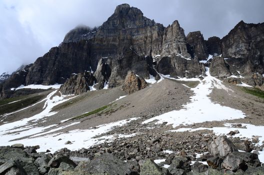 A stunning view of a rocky mountain peak with snow patches in Canada during winter.