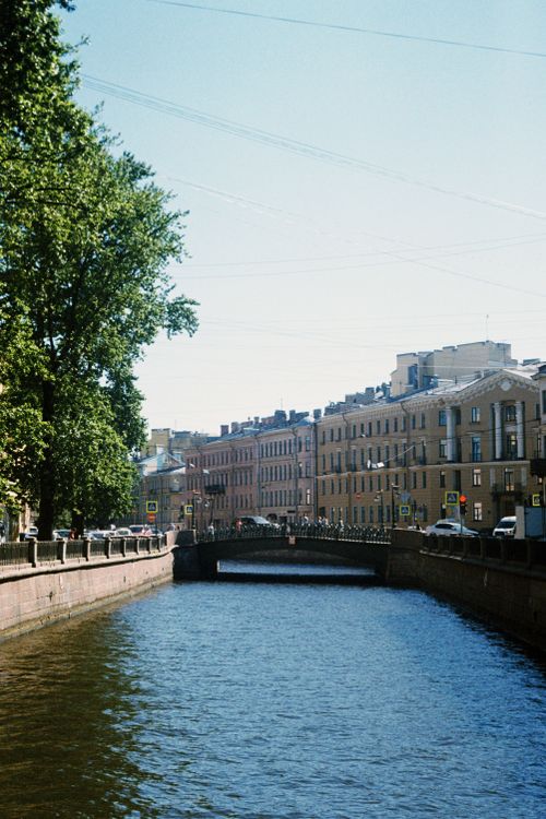 Free Scenic view of a canal flowing under a bridge flanked by historic buildings and trees. Stock Photo