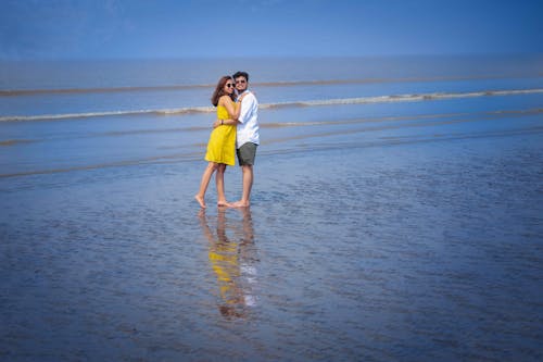 Free Man and Woman Standing Barefooted on Seashore Stock Photo